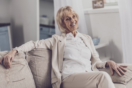 True relax. Experienced white collar worker feeling relaxed while having rest after work sitting on sofa in her living roomの写真素材