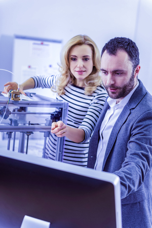 Just look. Delighted bearded man bowing head while looking at screen of computer