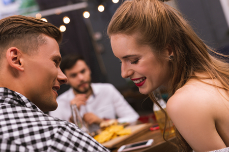 Flirting couple. Cheerful young people leaning to each other and smiling while flirtingの写真素材