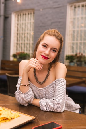 Attractive girl. Cheerful relaxed young girl smiling and feeling good while sitting at the bar...