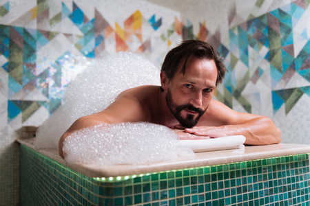 Spa procedure. Nice good looking man being in foam while having a special spa procedureの写真素材