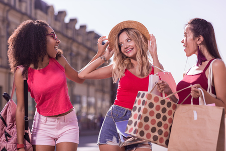 Is it beautiful. Positive joyful woman wearing a stylish hat while standing between her friendsの写真素材