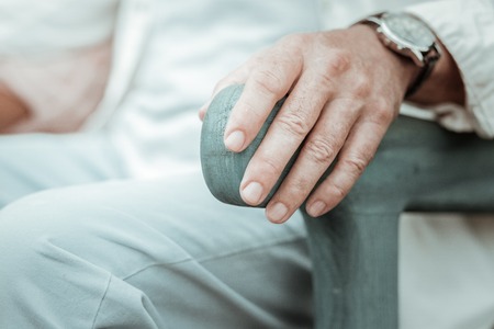 Feeling support. Senior man putting his hand on handle while having rest in parkの写真素材