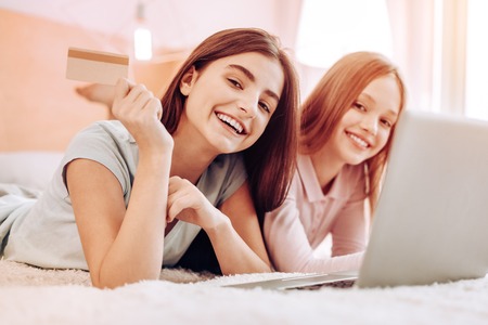 Express positivity. Pleased girl lying near her friend and posing on camera togetherの写真素材