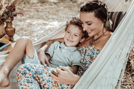 Cheerful people. Pleasant nice mother and child laughing at something having fun in a hammockの写真素材