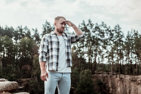 Look far away. Handsome bearded businessman concentrating while looking far away in the mountains...