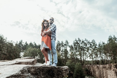 Comfortable sneakers. Cute young couple wearing comfortable sneakers standing on the edge of the cliff while traveling togetherの写真素材