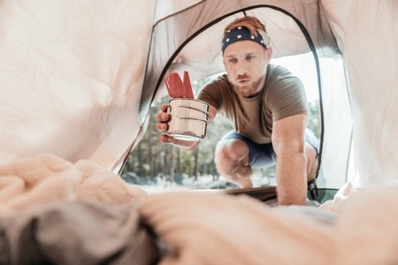 Caring hiker. Caring blonde-haired hiker wearing dark head band bringing some forks and spoons in...