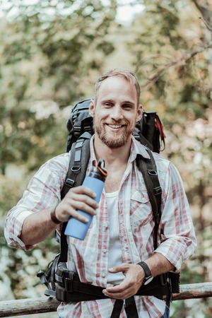 Refreshing water. Beaming handsome backpacker feeling really relived and rested after drinking...