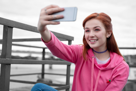 Cute selfie. Close up of cute long haired girl smiling to the camera and taking selfieの写真素材