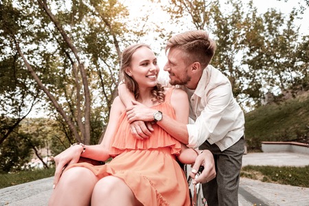 Falling in love. Kind loving man gently hugging his disabled girlfriend while standing next to her...
