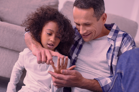 One two three. Joyful nice man pointing at his daughters finger while teaching her to countの写真素材