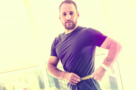 Attention. Confident attractive man measuring himself while exercisingの写真素材