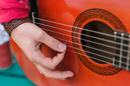 Wonderful melody. Close up of male tender hand holding mediator and picking strings