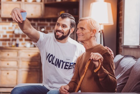 I love photographing. Handsome smiling man smiling and taking selfies with a pensionerの写真素材
