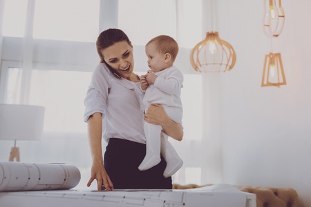 Freelance mother. Young freelance mother feeling active while speaking by phone spending time with daughterの写真素材