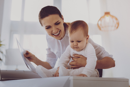 Beaming young cousin feeling cheerful laughing while playing with her little sister in living roomの写真素材