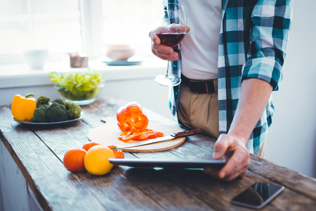 Glass of wine being in hands of a nice young man while relaxing at homeの写真素材