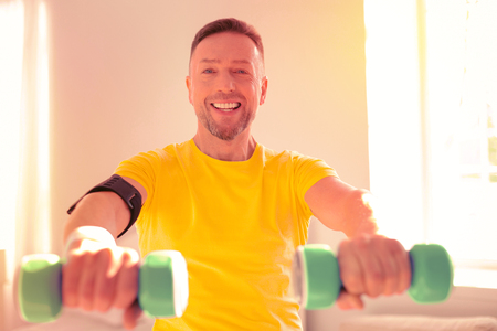 Smiling handsome man training while being at homeの写真素材