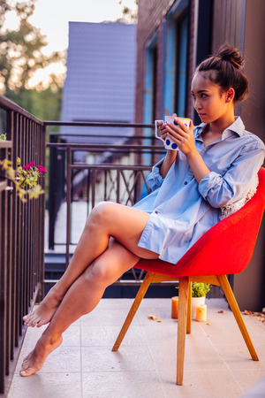 Nice beautiful woman sitting on the chair while enjoying her teaの写真素材