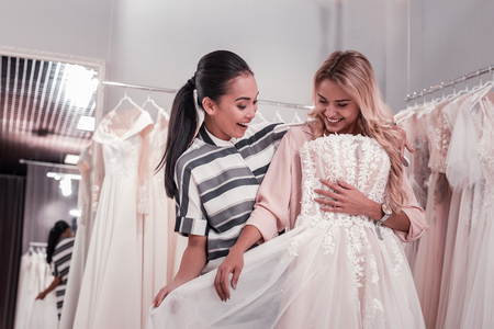 Nice young women feeling happy while finding a perfect wedding dressの写真素材