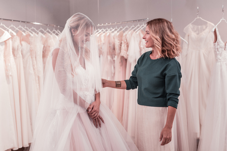 Positive joyful woman smiling while standing with her mother in a wedding dressの写真素材