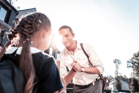 Stylish modern loving and caring father with tattoo on hand taking his little girl to school