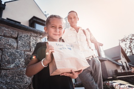 Beaming little girl feeling extremely cheerful and happy after receiving gift from her fatherの写真素材
