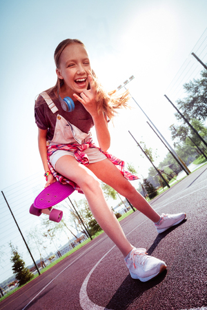 Pleased girl showing her arm and standing on basketball courtの写真素材