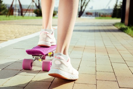 Close up. Sporty child having active day and testing her longboardの写真素材