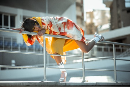 Stylish tanned woman unnaturally lying on the fence posing for photoshootの写真素材