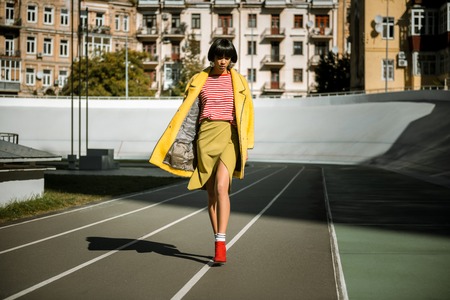 Carefree mixed race model walking around the stadium in designer clothing with bared legsの写真素材