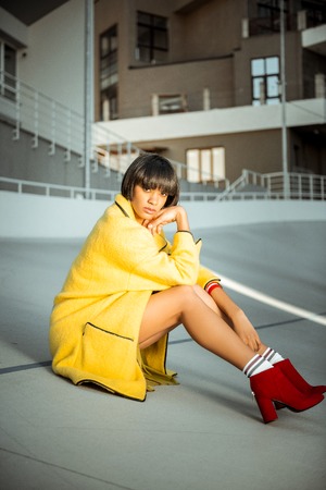Short-haired lady with long skinny hands sitting in closed unconstrained pose