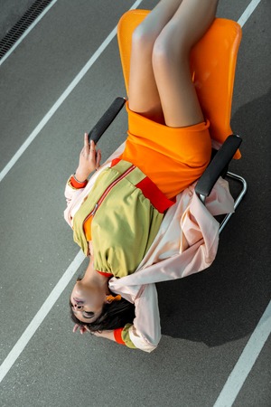 Interesting abnormal girl arching her body while lying on the chair with head over heelsの写真素材