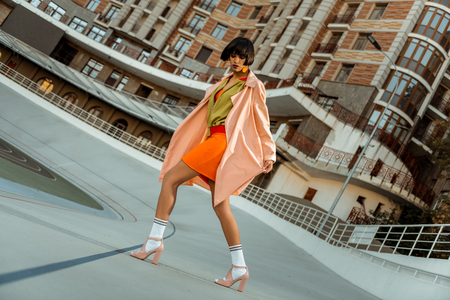 Colorful extraordinary chocolate woman widely stepping in pink shoes while spending time on stadiumの写真素材