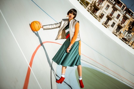 Resolute active lady standing on the stadium in layered look simulating sport gameの写真素材