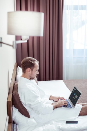 Busy successful businessman working on his laptop in hotel room while travelling for businessの写真素材