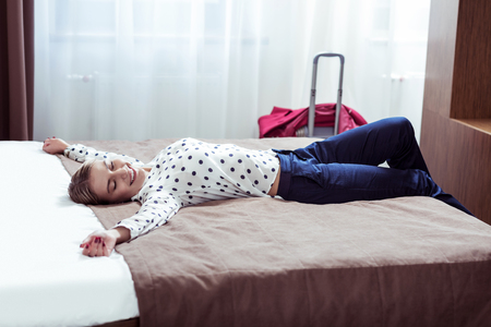 Elegant successful businesswoman on business trip coming to hotel and lying on bedの写真素材