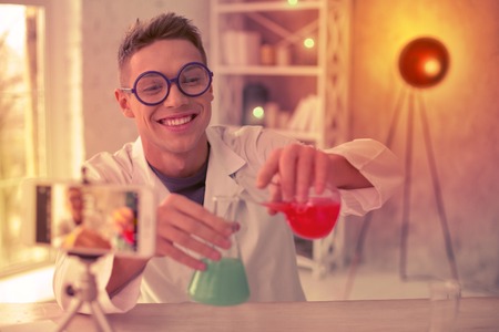 Smiling experimenter making a video about chemistry on his internet channel about scienceの写真素材