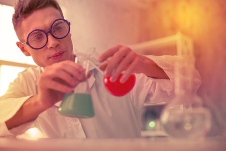 Unconfident handsome teacher blending reagents in glass tubes for chemistry experiment
