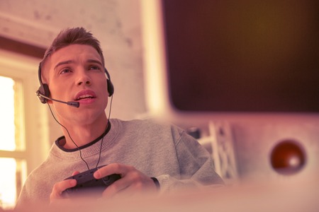 Discouraged young man looking on the screen while recording video for his internet channel