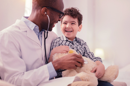 Cute friendly boy smiling while sitting on his fathers lapの写真素材