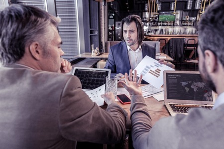 Man listen to pitch. Pleased brunette manager expressing positivity while working with his colleaguesの写真素材