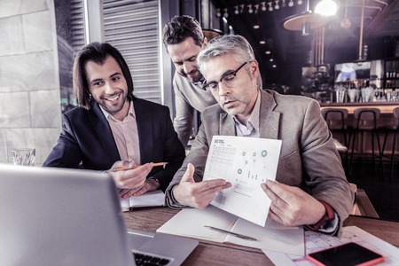 Modern presentation. Attentive competent worker bowing head while demonstrating his project