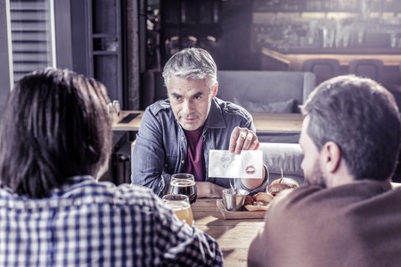 Telling the story about break up. Handsome man holding serviette in left hand while looking forward at friendsの写真素材
