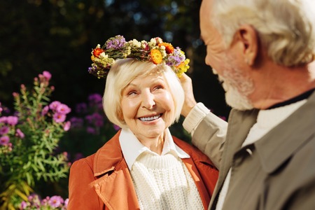 Happy grey haired woman smiling while receiving the gift from her husband