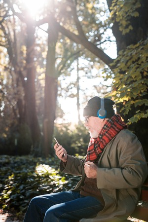 Nice joyful man sitting in the headphones while listening to music