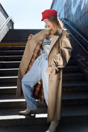 Baggy jeans. Slim dark-haired young model wearing baggy jeans and beige trench coatの写真素材