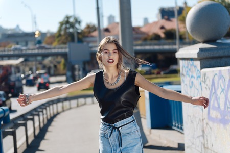 In the city. Beautiful young woman wearing high-waist jeans feeling amazing while walking in the cityの写真素材