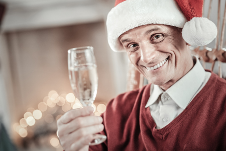 Merry Christmas. Attractive man wearing Santas hat and smiling while posing on cameraの写真素材